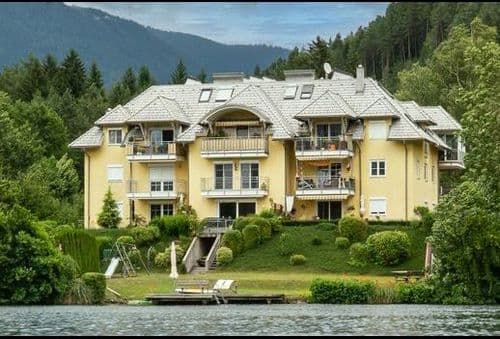Campingweg 7 - Willkommen in unserem modern und elegant gestalteten Wohnanlage, die von uns als Bauträger errichtet und verkauft wurden. Dieses Bild zeigt das schöne Äußere der modernen Gebäude, umgeben von Grün und Bäumen. Im Hintergrund können wir den klaren blauen Himmel und eine ferne Stadtlandschaft sehen. Diese Wohnanlage bietet luxuriöse Wohnräume, hochmoderne Annehmlichkeiten und eine friedliche Umgebung, die die Bewohner ihr Zuhause nennen können.